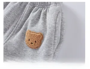 Dettaglio dei pantaloni sportivi grigi per bambini con elastico in vita e toppa a orsetto
