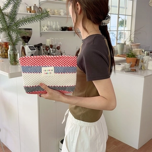 Model holding a vibrant red, white and blue striped pouch with a sozakka beauté label