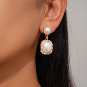 Detail of vintage gold pearl drop earring with rhinestones on model ear