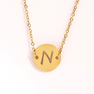 Vue détaillée d'un collier plaqué or avec un pendentif pièce creusé de la lettre N