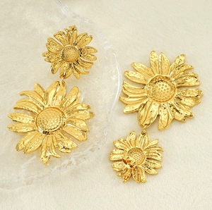 Detailed view of gold sunflower drop earrings with textured hammered finish on petals