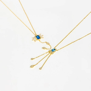 Detail of gold necklace featuring blue pear-shaped stones and white diamond accents