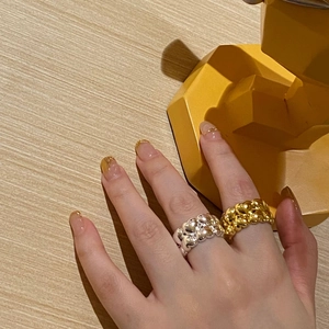Detail of gold and silver textured wide rings with irregular bubble surface on fingers