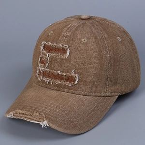 Distressed denim baseball cap with embroidered letters and torn brim details