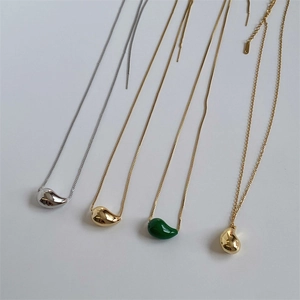 Detailed view of polished teardrop pendant necklaces in gold, silver and green colors