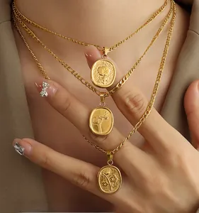 Détail des colliers dorés superposés avec pendentifs ovales aux reliefs de roses