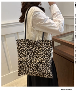 Detail of leopard print tote bag featuring slender black straps and golden ring accents