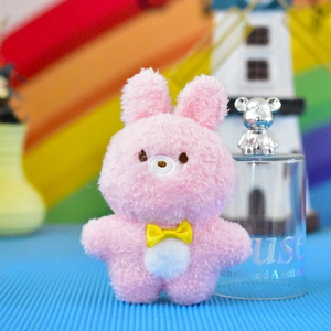 Dettaglio di un ciondolo di peluche a forma di coniglio rosa con fiocco giallo e texture