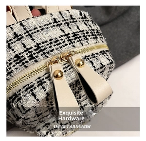 Close-up of black and white tweed fabric with golden metal studs and leather zipper pull