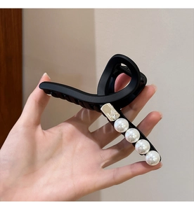 Gros plan d'une pince à cheveux noire mate avec d'élégantes perles blanches décoratives