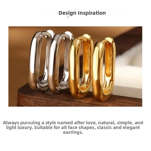 Detailed view of polished gold and silver S925 sterling silver oval hoop earrings on a box