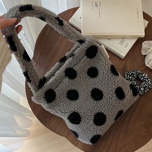 Vue détaillée du sac à main en peluche gris doux à pois noirs sur une table en bois