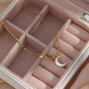 Detailed view of gold crescent moon necklace with zircon in a pink velvet jewelry box