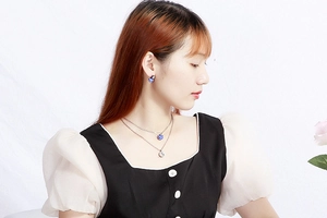 Silver multi-layer necklace and earrings set featuring blue patterned spherical charms on a model