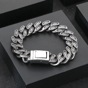Detailed macro view of silver Cuban chain bracelet with textured relief on black stand
