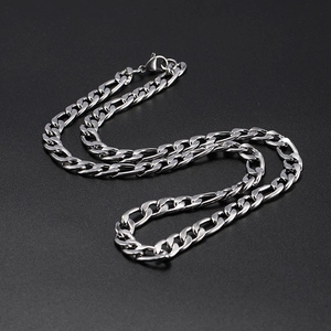 Detail of silver Figaro chain necklace in stainless steel on black textured surface