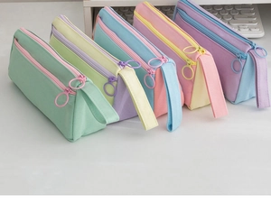 Detail of color-block canvas pencil case with double zippers and large metal rings