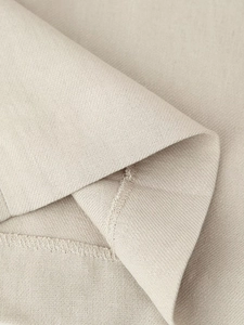 Close-up of beige woven fabric texture and high-quality stitching on sleeveless top suit