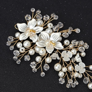 Close-up of white flowers, pearls and crystals hand-woven on gold wire bridal headband