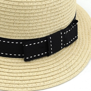 Close-up of natural straw weave texture and black grosgrain ribbon with white stitching