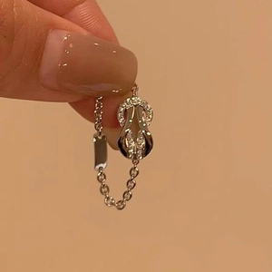 Detailed macro view of a silver link ring featuring an iced-out horseshoe knot charm