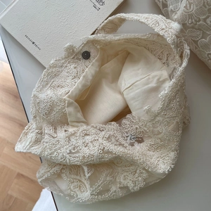 Detail of floral lace embroidery tote bag with magnetic metal clasp and inner lining