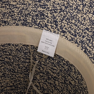 Détail d'un chapeau de paille tissé main avec bande de confort et étiquette d'entretien
