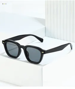 Detail of classic black square sunglasses featuring gold rivet accents on polished frames