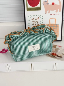 Green and white plaid quilted storage bag with vibrant orange ruffle lace and woven label