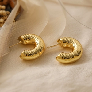 Detail of 18K gold plated C-shaped earrings featuring a vintage hammered metal texture