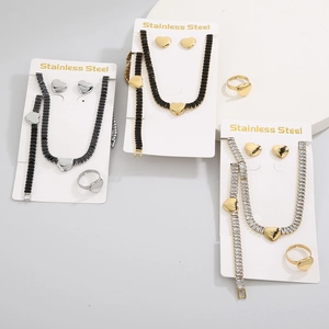 Détail de parures de bijoux coeur en acier inoxydable doré avec pierres noires et blanches