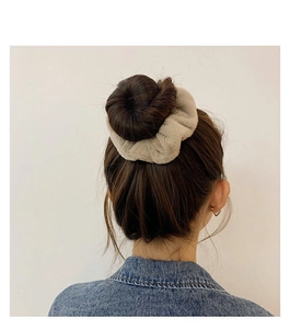 Close-up of fluffy faux rabbit fur scrunchie in beige worn on a high bun hairstyle