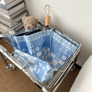 Blue plaid sun umbrella with floral pattern and wooden handle in a lifestyle setting
