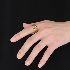 Close-up of a wide hollow cuban chain ring in gold finish worn on a finger