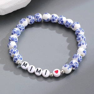 Dettaglio di perle in ceramica a fiori blu con lettere MIMI e cuore rosso su un braccialetto