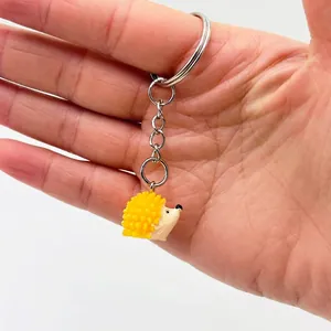 Cute cartoon hedgehog keychain with yellow textured spikes and a silver metal chain ring