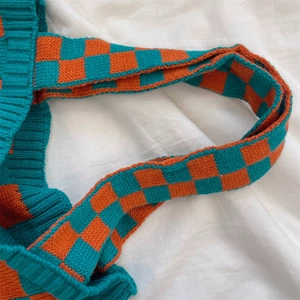 Detail of blue and orange checkered knit tote bag showing thick woven texture and strap