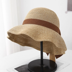Detail of light khaki woven straw sun hat with elegant dark brown decorative ribbon