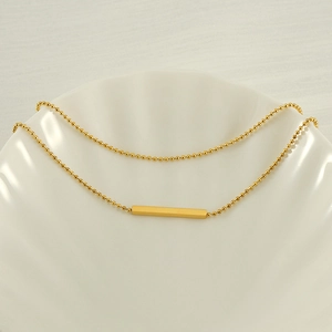 Detail of 18K gold double layer T-bar pendant necklace on white seashell display plate