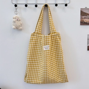 Close-up of yellow plaid canvas tote bag with sozakka beaute label and sheep charm