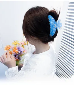 Detail of blue large hair claw clip with daisy floral print worn on a model's hair