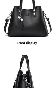 Vues de face et de profil d'un sac Boston noir grainé avec un pendentif coeur en argent