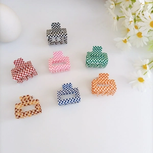 Flat lay of small checkered acrylic hair claws in multiple colors with daisy accents