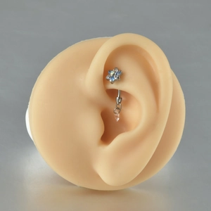 Detailed macro of a flower-shaped G23 titanium ear stud with a teardrop pendant on ear model