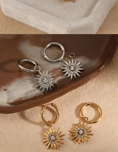 Detail view of gold and silver sunburst drop hoop earrings with zircon stones