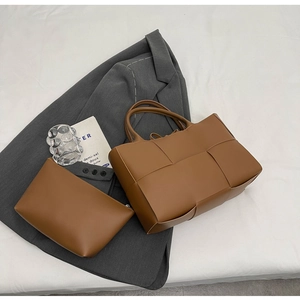 Detailed view of brown woven tote bag set with matching inner pouch on grey blazer
