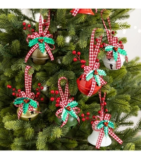 Detail of Christmas metal bells with houndstooth bows and holly berries on tree branches