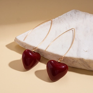 Close-up of elegant deep red heart-shaped earrings on a marble stone surface