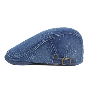 Detail of dark blue denim newsboy cap showing vintage distressed texture and side metal buckle