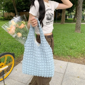 Detail of light blue bubble texture tote bag in a casual outdoor park setting
